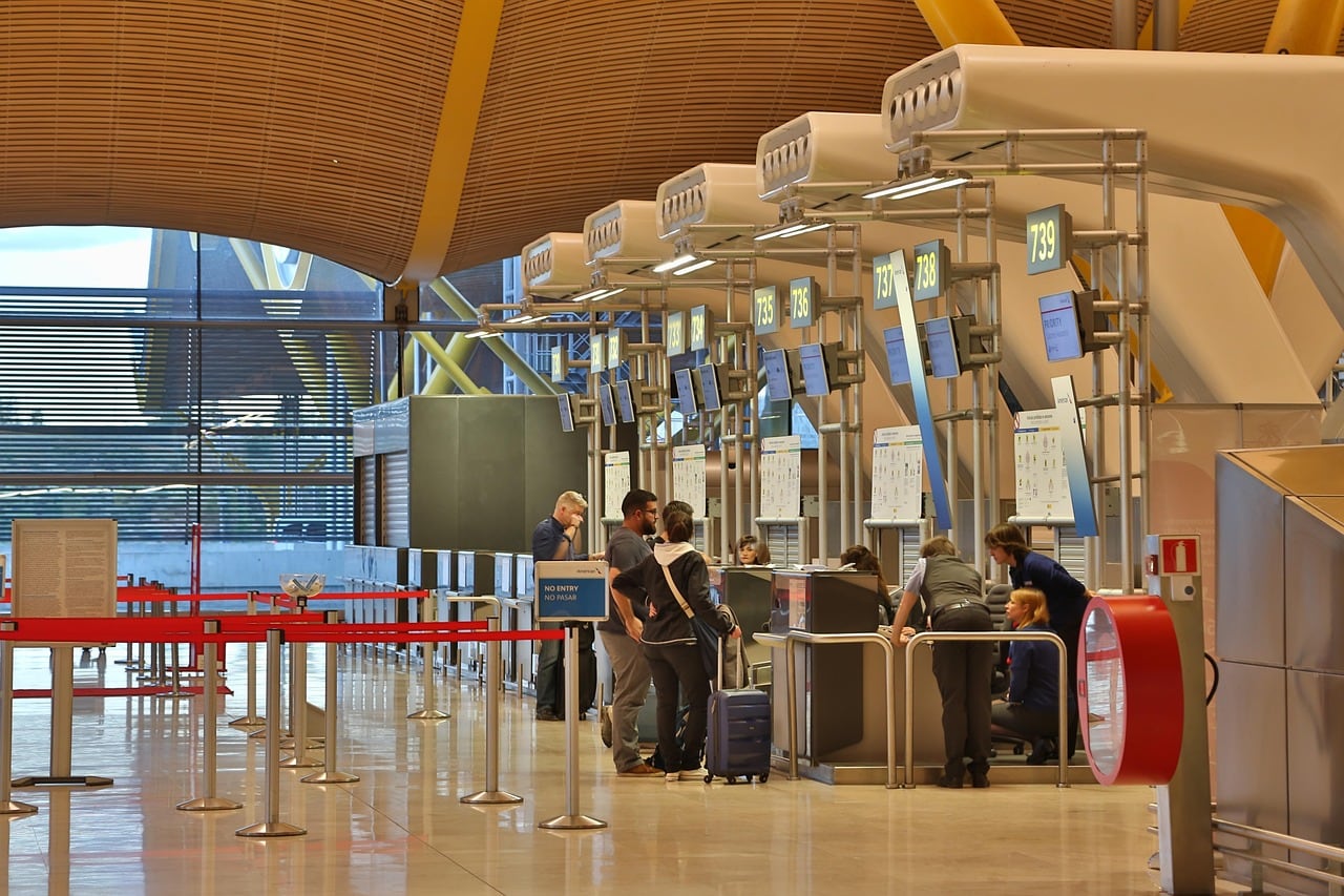 Pasajeros con maletas revisando documentación en la zona de facturación de un aeropuerto