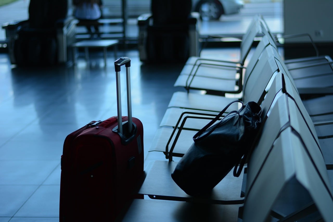 Mostradores de facturación vacíos en un aeropuerto con pasajeros esperando